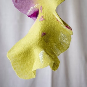 May include: A yellow felt fabric with a pink and white design. The fabric is draped and has a ruffled edge.