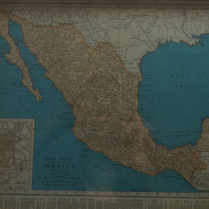 May include: A framed vintage map of Mexico, featuring detailed geographical information. The map, with a blue ocean and tan landmass, includes a smaller inset map and text that reads "Rand McNally Popular Map of Mexico."