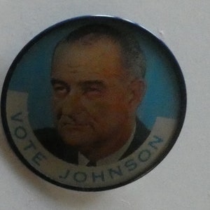 May include: A blue and white round button with a picture of Lyndon B. Johnson and the text "Vote Johnson" around the edge.