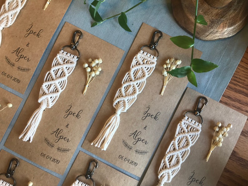 May include: White macrame keychains with a tassel on a brown card with the text "Ipek & Alper 06.04.2019" printed on it.