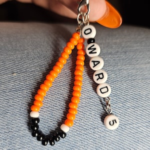 May include: Orange and black beaded keychain with the name "WARD" and the number "5" on white beads.