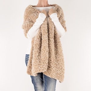 May include: A beige fluffy knit scarf draped around a person's neck. The scarf is soft and fluffy, and it would be perfect for keeping warm in the winter.