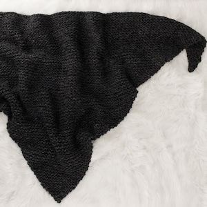 May include: A dark grey triangular knitted shawl or scarf made of a soft yarn.