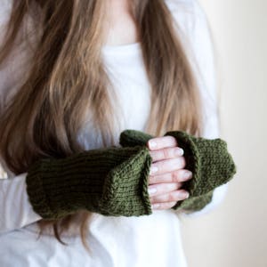 Könnte beinhalten: Ein Paar olivgrüne gestrickte Fingerlose Handschuhe mit einem Umschlag.