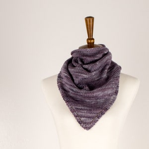 May include: A purple and grey striped knitted scarf with a scalloped edge, displayed on a white mannequin.