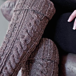 May include: A pair of brown knitted leg warmers with a cable knit pattern.