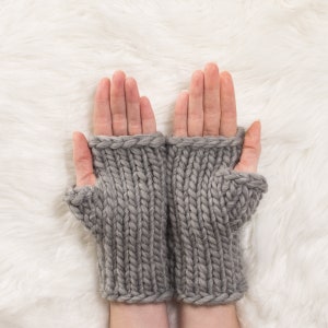 Könnte beinhalten: Ein Paar graue fingerlose Strickhandschuhe mit Rippenstruktur.