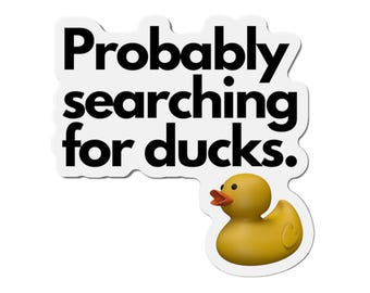 Puede incluir: Adhesivo blanco con el texto negro "Probably searching for ducks." y una ilustración de pato de goma amarillo con pico naranja. Fondo blanco.