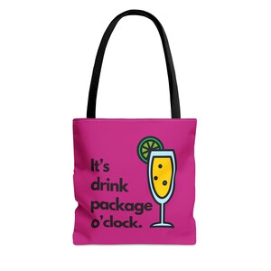 Pode incluir: Sacola tote rosa com alça preta e o texto "It's drink package o'clock."  Uma ilustração de desenho animado de uma taça de champanhe com uma fatia de limão está ao lado do texto.