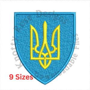 May include: A blue embroidered patch with a yellow trident, the coat of arms of Ukraine. The patch is shaped like a shield and has a textured fabric.