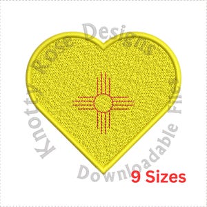 Puede incluir: Un parche amarillo en forma de corazón con la bandera del estado de Nuevo México. La bandera presenta un símbolo Zia rojo con un sol amarillo en el centro.