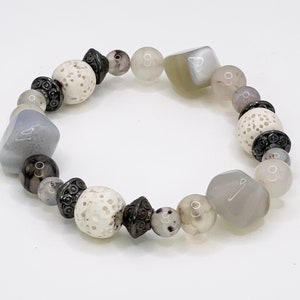 May include: A gray, white, and black beaded bracelet with lava rock beads and faceted agate beads.