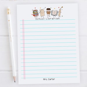 May include: A white notepad with blue horizontal lines and two pink vertical margin lines. The top features cartoon illustrations of books, a card, a coffee cup, and a bookmark with the text School Librarian. The bottom reads Mrs. Carter.