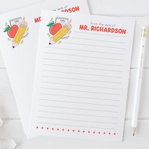 May include: A white lined notepad with a red apple and yellow pencil illustration. The text "From the desk of MR. RICHARDSON" is at the top of the notepad.