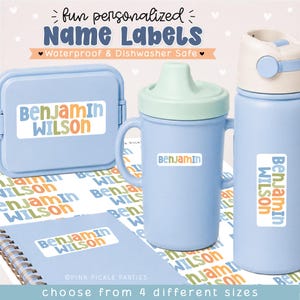 May include: A set of personalized name labels featuring the text "BENJAMIN WILSON" in blue, orange, and green. The labels are applied to a light blue snack container, a light blue sippy cup, a light blue water bottle, and a spiral-bound notebook.