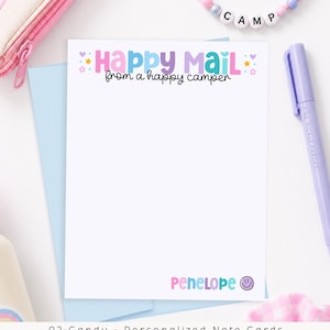 May include: A white rectangular note card featuring the text Happy Mail from a happy camper in colorful letters at the top, with small stars and hearts. The name Penelope is printed in the bottom right corner next to a purple smiley face icon.