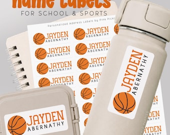 May include: Personalized name labels for school and sports. The labels feature a basketball graphic and the name "JAYDEN ABERNATHY". The labels are shown on a water bottle, a notebook, and a small container. The text "03-Basketball Solid" is also visible.