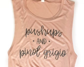 May include: A blush pink sleeveless tank top with the text "pushups and pinot grigio" printed in black.