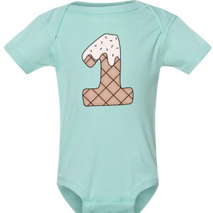 May include: A light blue baby onesie with a graphic of the number one shaped like an ice cream cone with sprinkles on top.