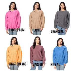 May include: Six women are wearing different colored sweatshirts. The colors are bubble gum pink, latte, charcoal, light orange, maroon, and royal blue. The sweatshirts are all the same style, with a crew neck and long sleeves.