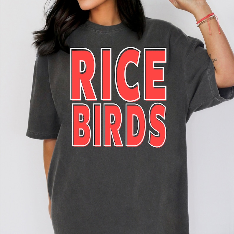 K&ouml;nnte beinhalten: Ein schwarzes T-Shirt mit dem Aufdruck "RICE BIRDS" in Rot mit wei&szlig;em Umriss.