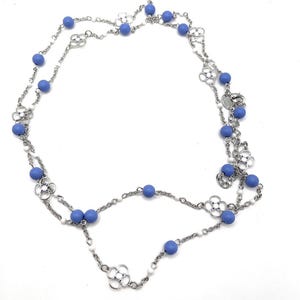 May include: A silver chain necklace with blue beads and silver flower charms. The necklace is double-stranded.