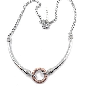 Puede incluir: Un collar de plata con un colgante circular de oro rosa. El collar tiene un diseño de cadena de eslabones y un diseño de barra curva.