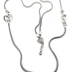 Puede incluir: Un collar plateado con un dise&ntilde;o de cadena trenzada. El collar presenta eslabones decorativos y estilizados a intervalos a lo largo de la cadena. El collar tiene una longitud ajustable con un peque&ntilde;o dije en forma de coraz&oacute;n al final.