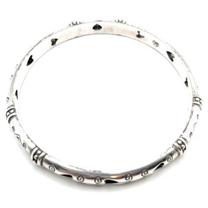 Pu&ograve; includere: Un braccialetto rigido in argento con un design decorativo di cuori e spirali.