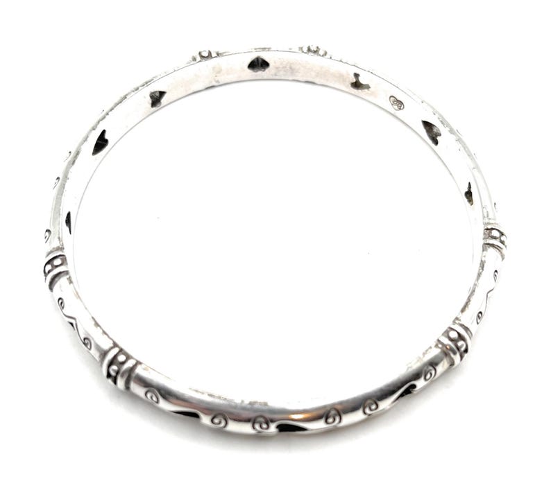 Pu&ograve; includere: Un braccialetto rigido in argento con un design decorativo di cuori e spirali.