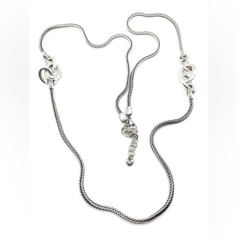 Puede incluir: Un collar plateado con un dise&ntilde;o de cadena delicada. El collar presenta elementos decorativos en cada extremo y una secci&oacute;n central ajustable. El dise&ntilde;o es intrincado y elegante, adecuado para diversas ocasiones. Longitud de la cadena: aprox. 60 cm.