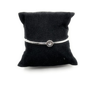 Puede incluir: Un brazalete de plata con un cristal transparente engastado en un dise&ntilde;o de flor de plata.