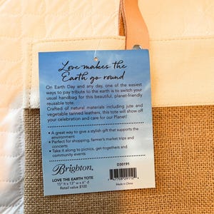 Puede incluir: Una bolsa de mano marr&oacute;n y beige con un asa de cuero marr&oacute;n. La bolsa est&aacute; hecha de materiales naturales, incluyendo yute y cuero curtido vegetal. La etiqueta de la bolsa dice "Love makes the Earth go round" y "Love the Earth Tote". La etiqueta tambi&eacute;n incluye las dimensiones de la bolsa: 38 cm x 33 cm x 15 cm. El valor de venta al p&uacute;blico es de 100 &euro;.