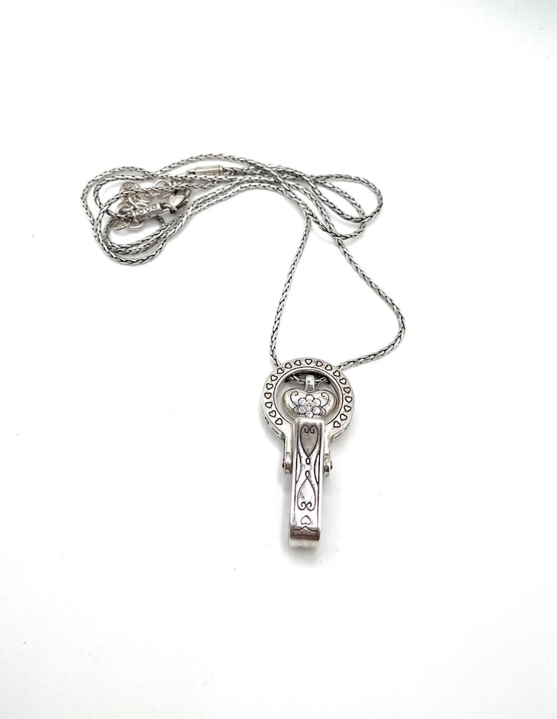 Puede incluir: Collar con colgante de llave plateada. El colgante en forma de llave presenta un dise&ntilde;o de corona con detalles de coraz&oacute;n y flores. La cadena del collar es de estilo delicado y tejido. El colgante mide aproximadamente 3,8 cm de largo.