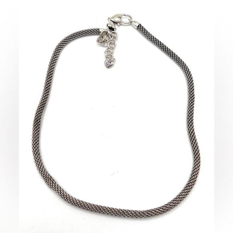 Może przedstawiać: Srebrny naszyjnik z delikatnym, plecionym łańcuszkiem. Łańcuszek ma około 45 cm długości i zapinany jest na karabińczyk.