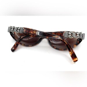 Puede incluir: Gafas de sol carey con lentes marrones. Las monturas presentan adornos decorativos plateados en las patillas. Las varillas tienen un patr&oacute;n carey a juego. Un accesorio elegante para la protecci&oacute;n ocular.