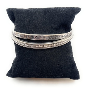 Peut inclure: Deux bracelets en argent, l'un avec un motif en spirale et l'autre avec une rang&eacute;e de strass transparents.