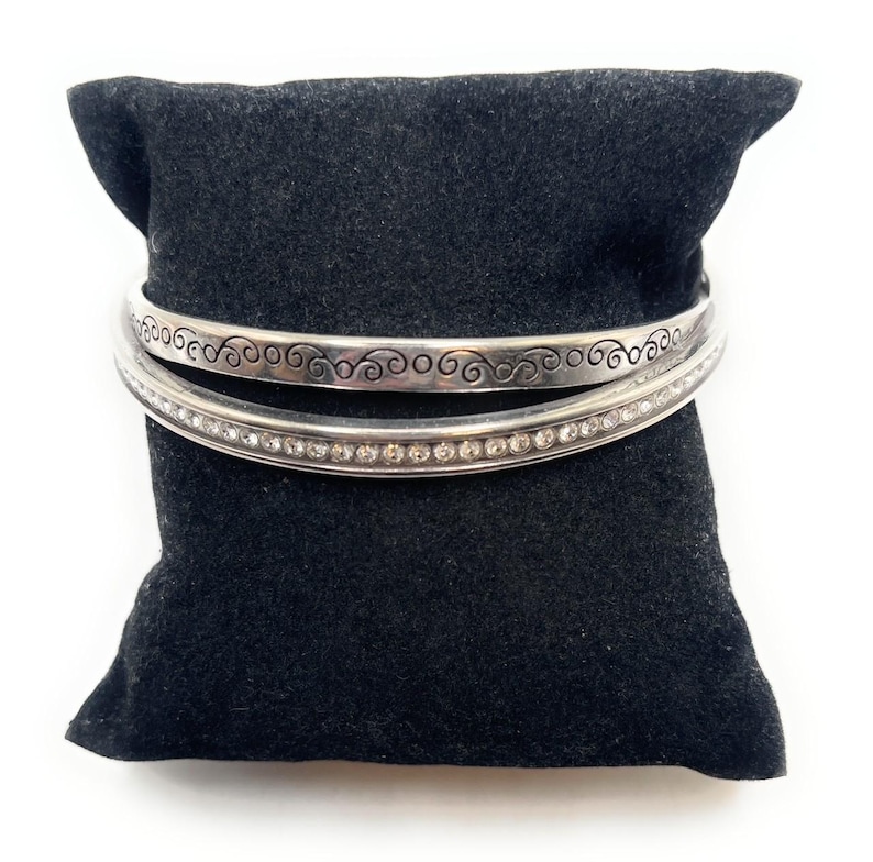 Peut inclure: Deux bracelets en argent, l'un avec un motif en spirale et l'autre avec une rang&eacute;e de strass transparents.