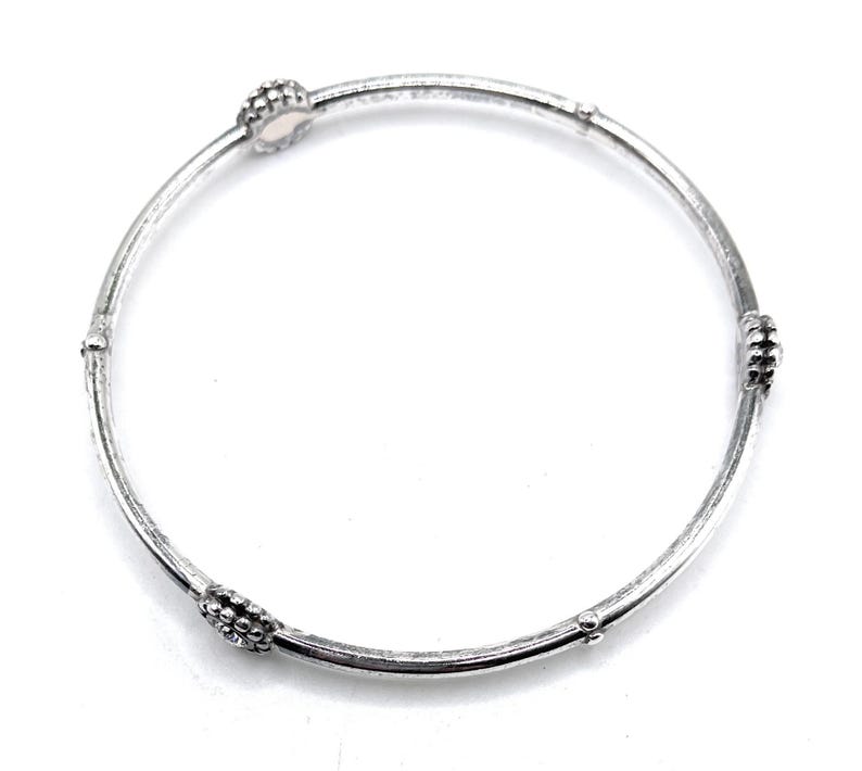 Puede incluir: Un brazalete de plata con cuatro acentos redondos texturizados.