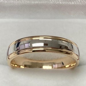 May include: A two-tone wedding band with a polished silver finish and a thin band of gold around the edge.