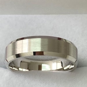 May include: A silver wedding band with a brushed finish and a beveled edge.