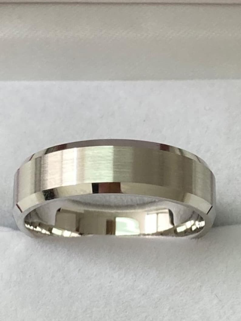 May include: A silver wedding band with a brushed finish and a beveled edge.