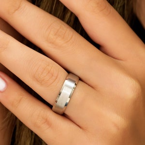 May include: A silver wedding band with a brushed finish.