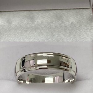 May include: A silver wedding band with a bevelled edge and a polished finish.