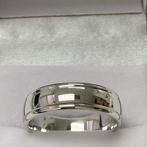 May include: A silver wedding band with a bevelled edge and a polished finish.