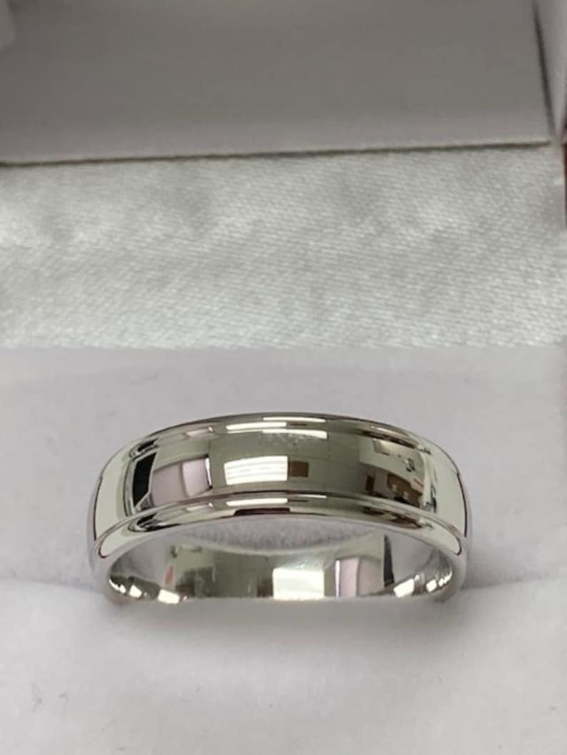 May include: A silver wedding band with a bevelled edge and a polished finish.