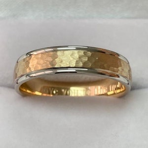 May include: A two-tone gold wedding band with a hammered finish. The band is made of both white and yellow gold.