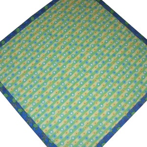 May include: A square fabric bandana featuring a diagonal pattern of alternating light green and yellow stripes. The design is accented with small blue and white flower motifs. A dark blue border frames the piece, decorated with green turtle icons.