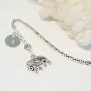 May include: Silver bookmark with a decorative elephant charm, a small round charm with the letter 'S' and a beaded chain.
