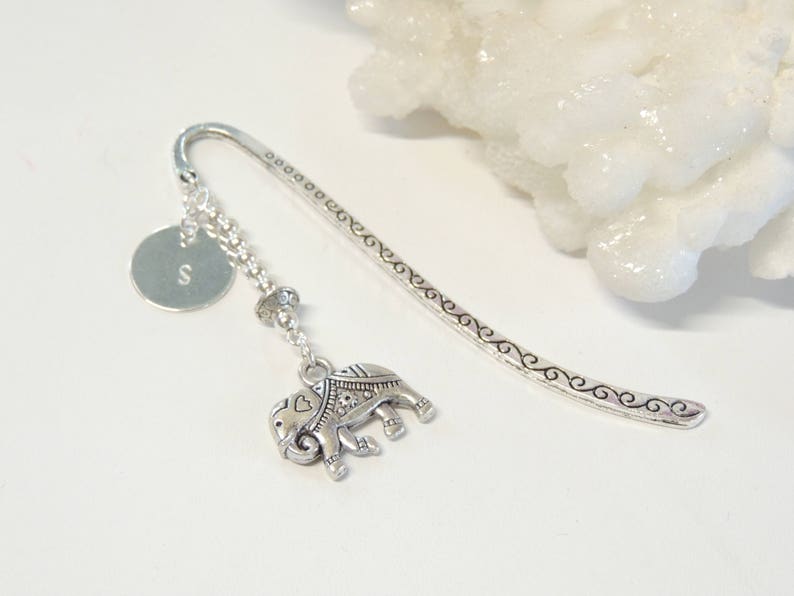 May include: Silver bookmark with a decorative elephant charm, a small round charm with the letter 'S' and a beaded chain.